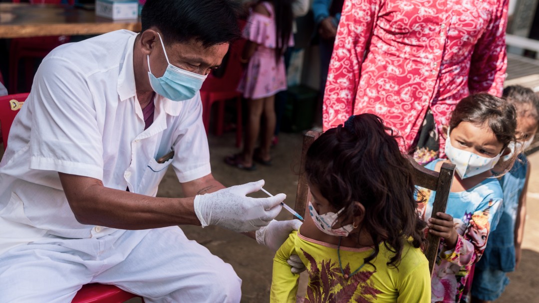 Children are vaccinated against COVID-19 in front of a health centre in Battambang.
