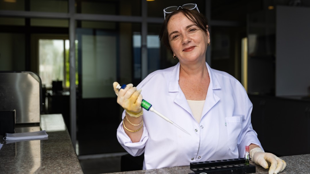 Eine Frau steht m it einer Spritze in der Hand in einem Labor