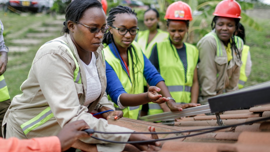 Afrikanische Arbeiterinnen mit Helmen arbeiten an einem Dach