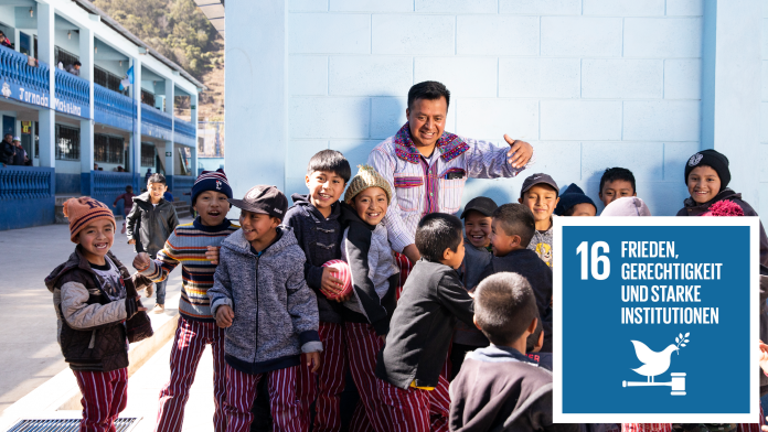 Fröhliche Kinder mit ihrem Lehrer vor einem Schulgebäude in Guatemala, daneben das SDG16-Icon: Frieden, Gerechtigkeit und starke Institutionen