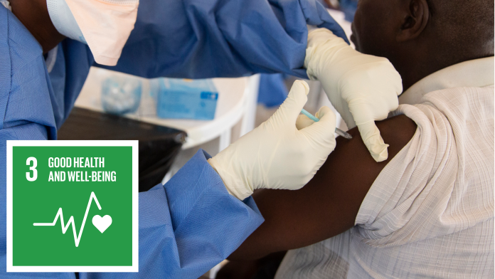 Laboratory assistant fills a liquid into the test tube with a pipette, next to it the icon of SDG 3: Health and well-being