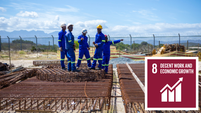 African construction workers on a building site, next to them SDG 8 icon: Decent work and economic growth