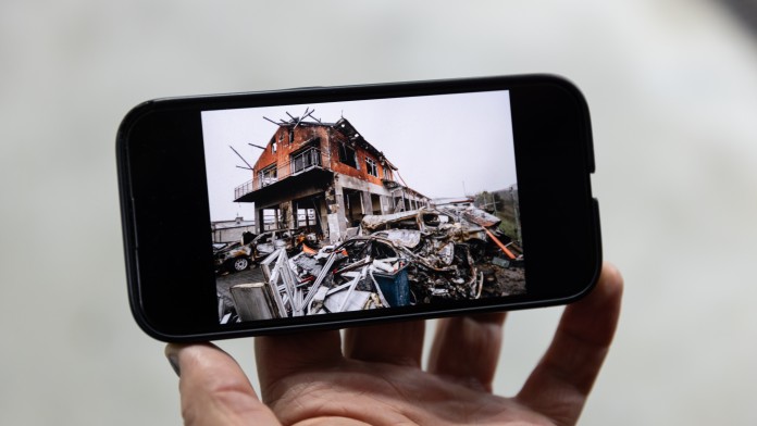 Ein Smartphone zeigt ein Bild von einer zerstörten Autowerkstatt