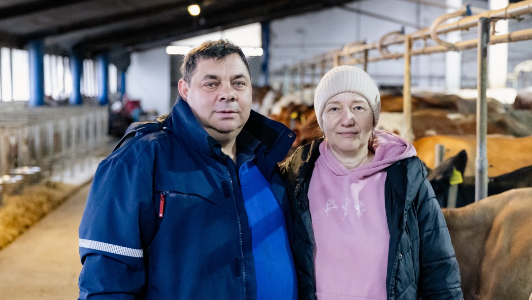 Ein Mann und eine Frau stehen im Mittelgang eines Kuhstalls.