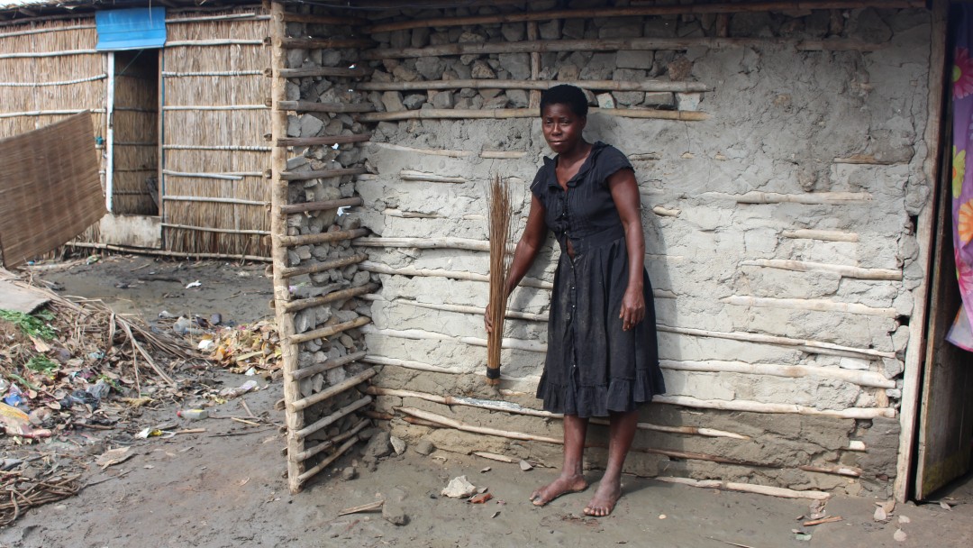 An african woman shows with her broom the water level of the last flooding