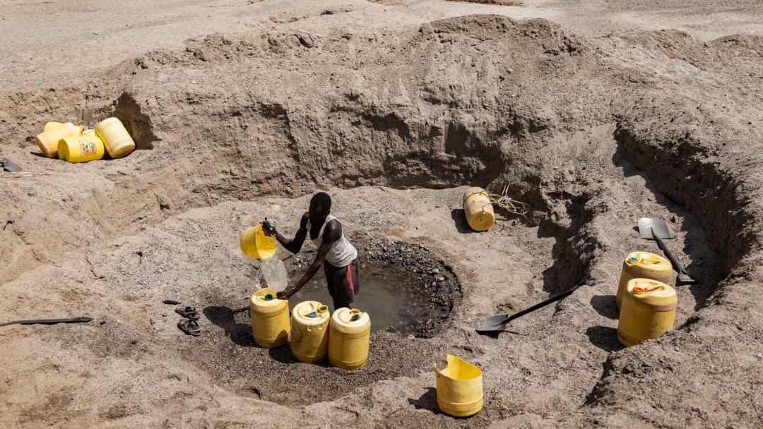 Menschen sammeln Grundwasser aus selbst gegrabenen Brunnen in einem ausgetrockneten Flussbett naher der Stadt Kakuma, Region Turkana, Kenia 2021 