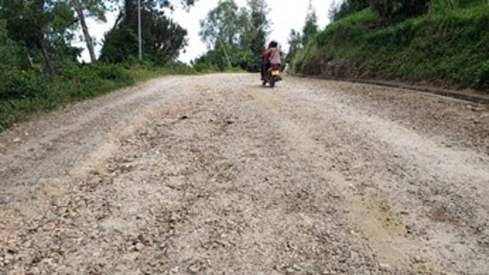 Person auf Motorrad fährt eine rehabilitierte, unbefestigte Straße entlang