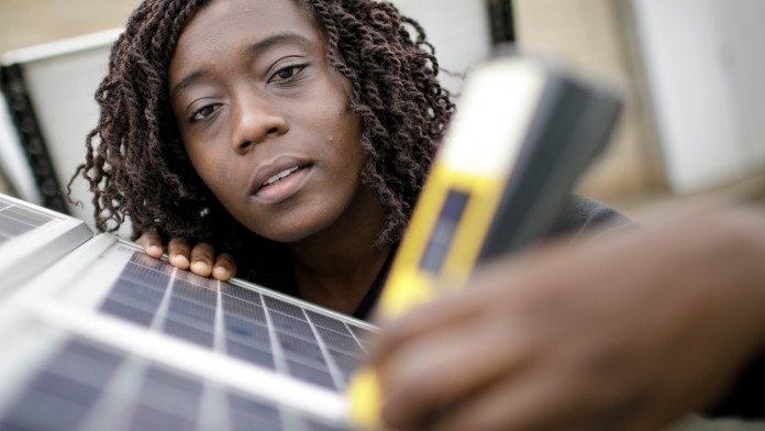 Female engineer using measuring device on solar panel
