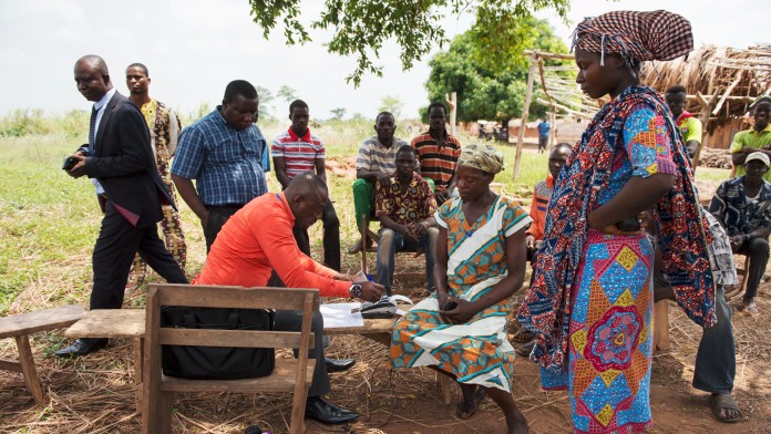 The cashier at the local bank pays out government social grants to farmers in the village of Adukram, Ashanti Region, Ghana, via e-zwich.