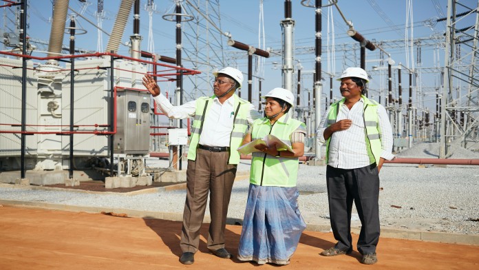 Three people in front of a substation in Hindupur, India
