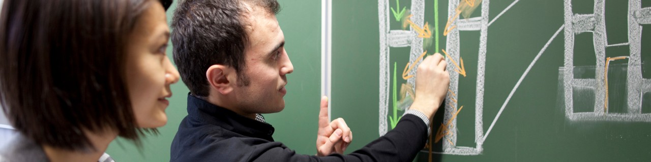 A woman and a man in front of a blackboard