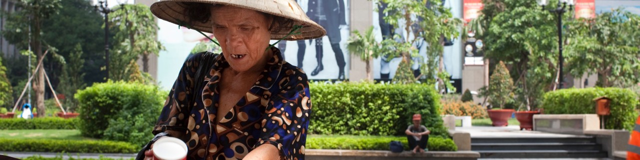Eine asiatische Frau durchsucht einen Mülleimer