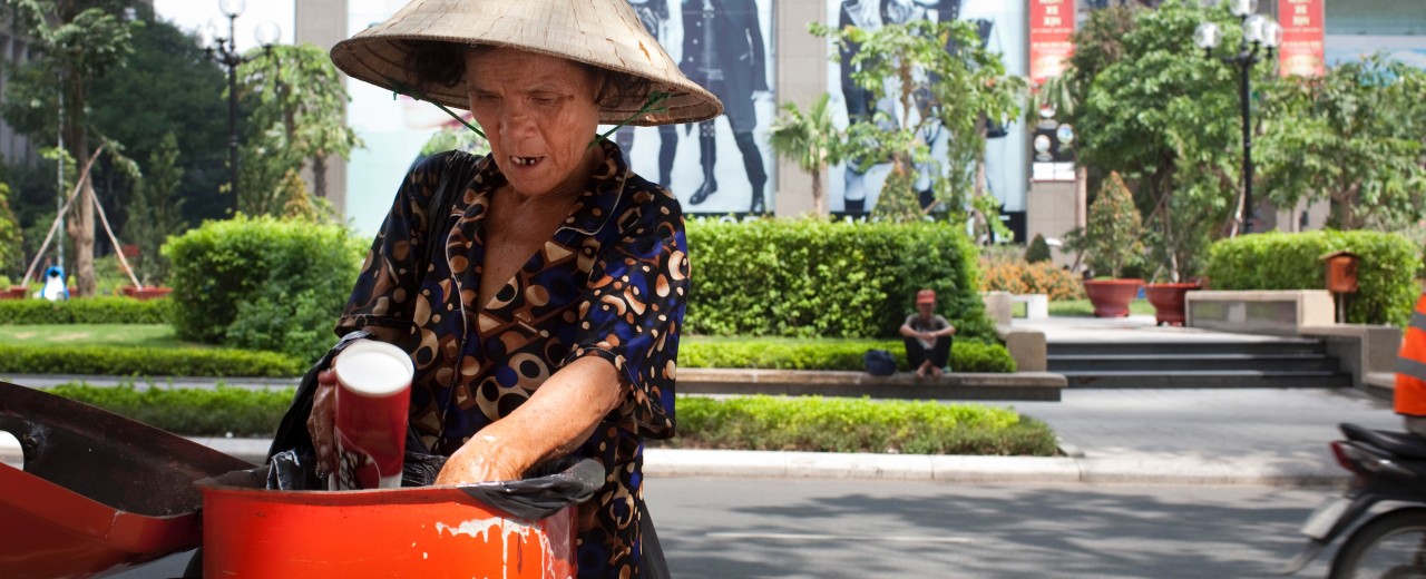 Eine asiatische Frau durchsucht einen Mülleimer