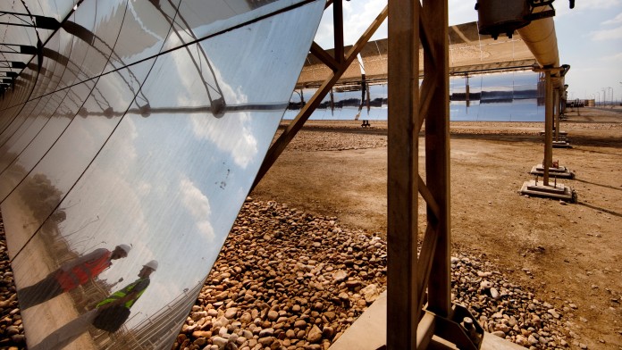 Solarpaneele in einem Sonnenkraftwerk, Arbeiter spiegeln sich in den Solarzellen