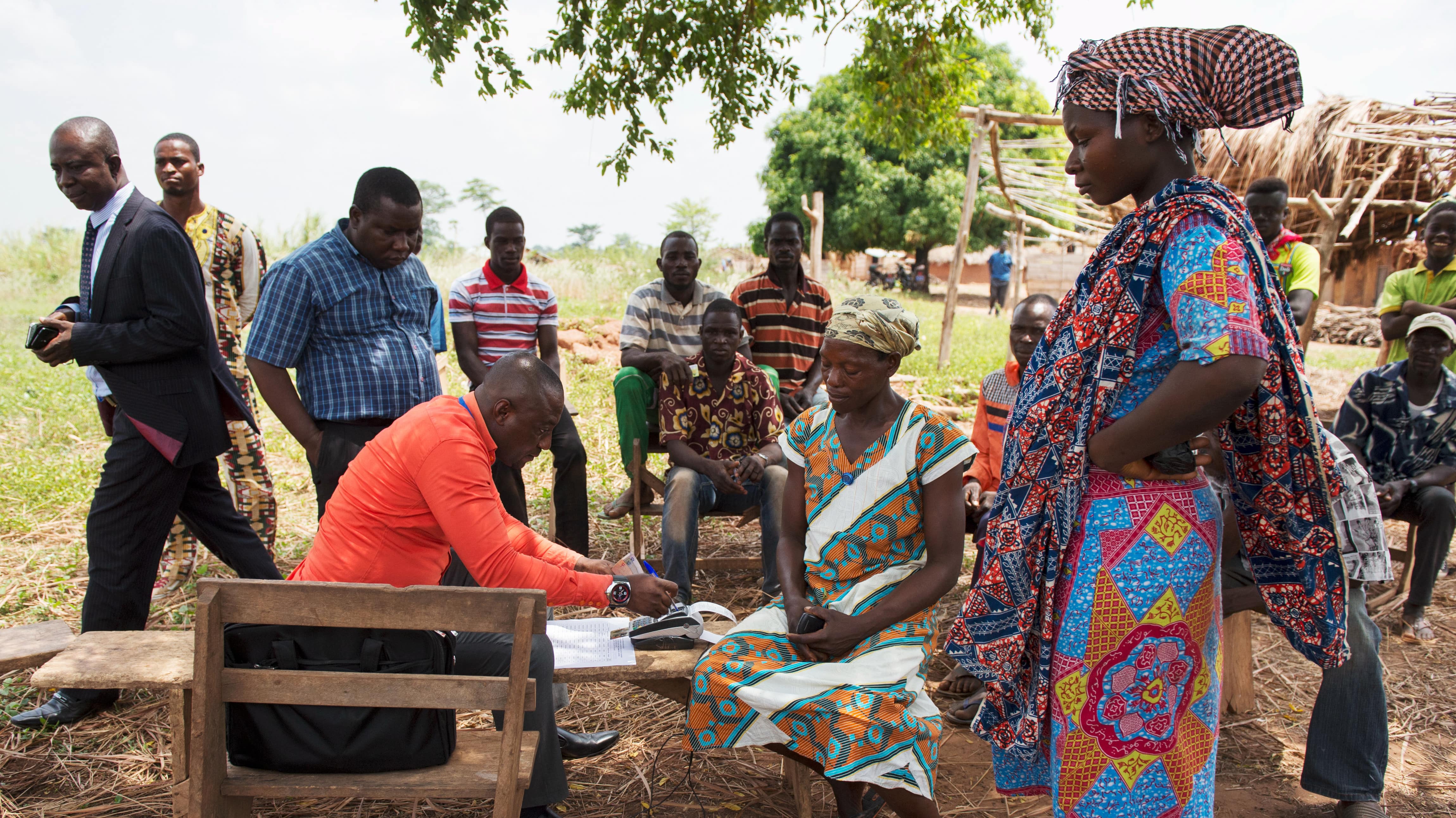 Der Kassierer der lokalen Bank zahlt Bauern im Dorf Adukram, Region Ashanti, Ghana, per e-zwich die staatliche Sozialförderung aus.